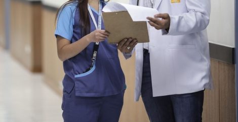 Two health professionals looking at notes on a clipboard